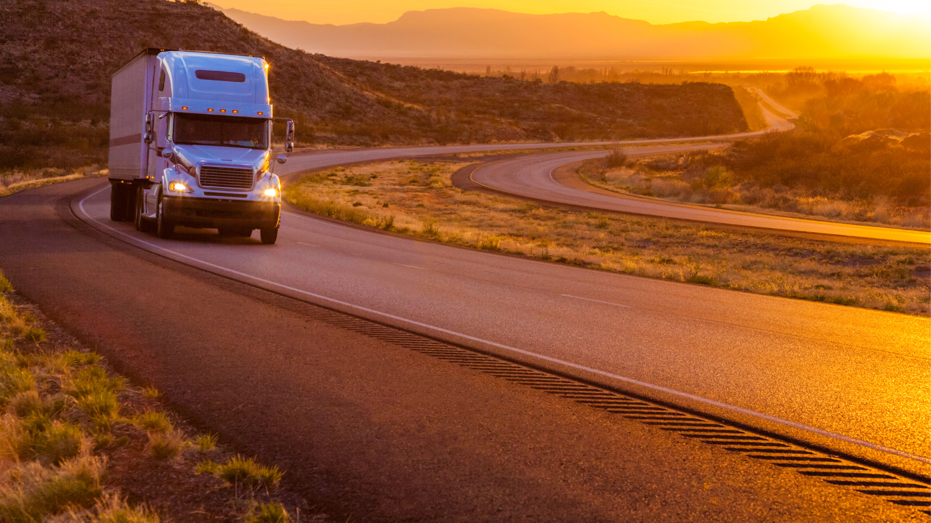 Truck driving on a highway at sunset